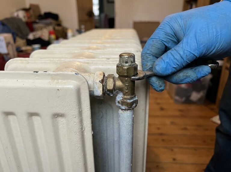 Heizungsinstallateur prüft ein Ventil an einem Heizkörper